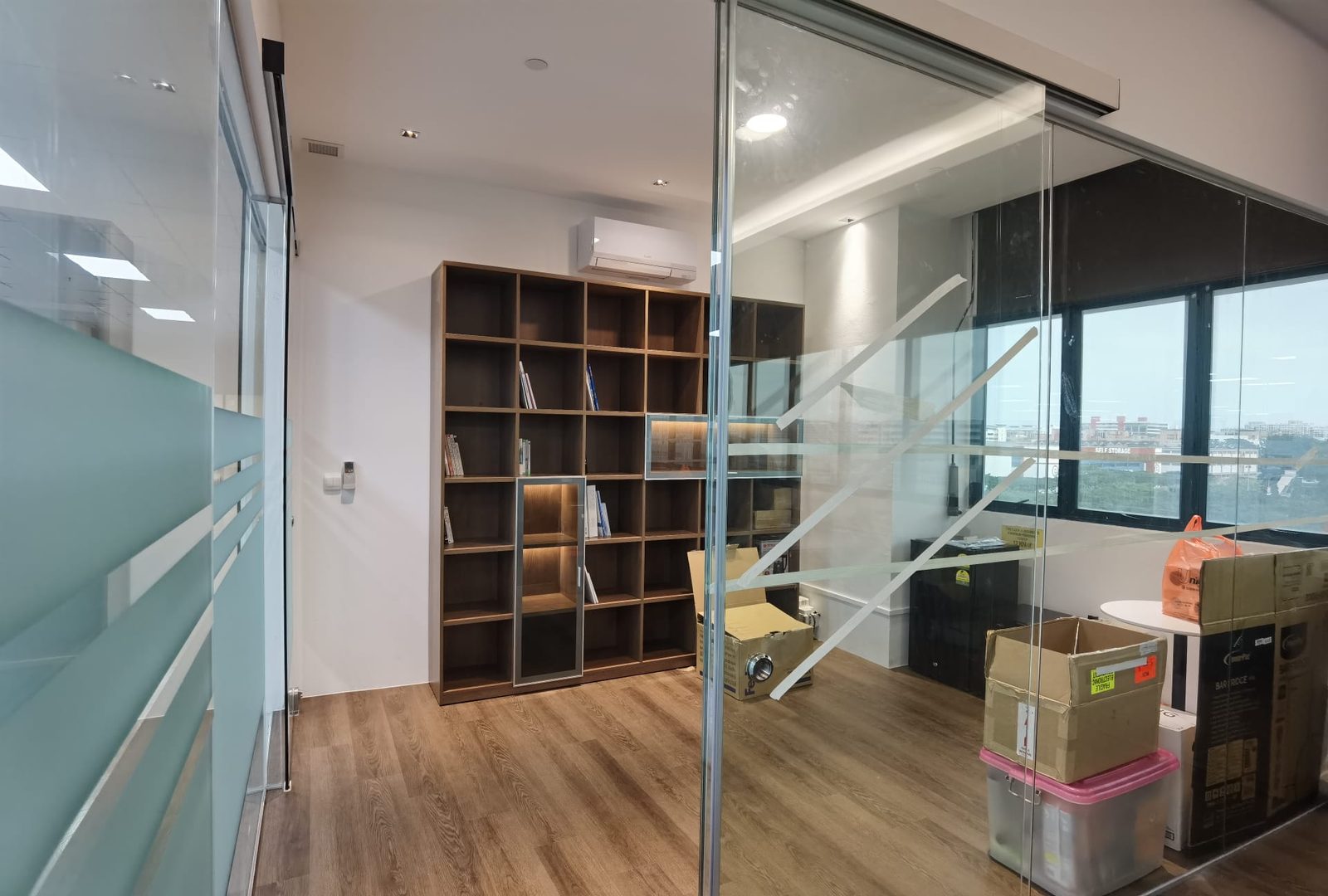 Office fit-out with glass partitions and a built-in timber bookshelf